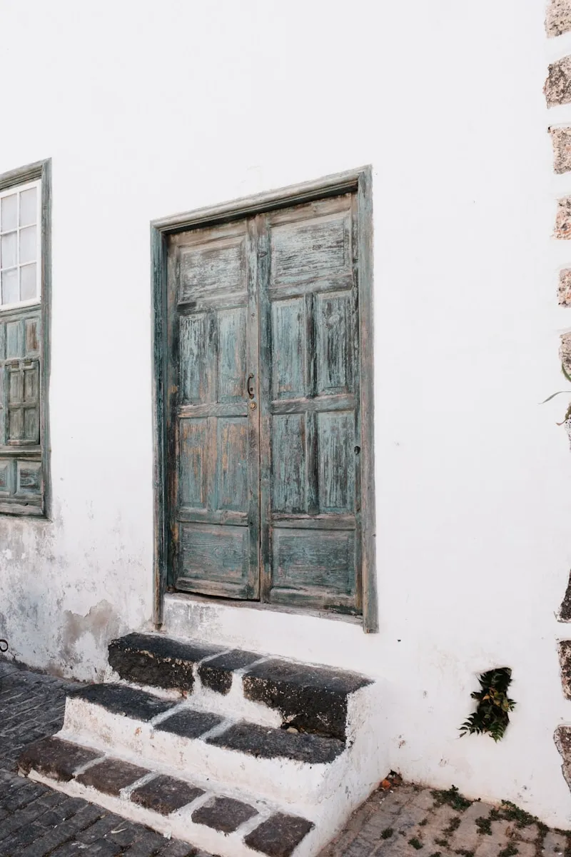 A white building with two windows and a bench in front of it