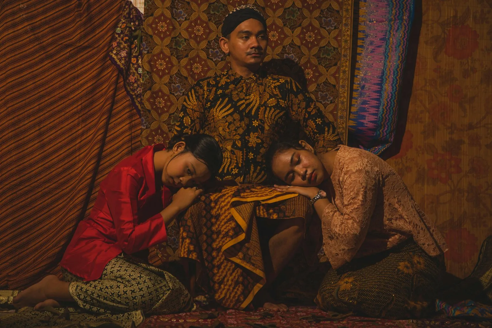 a man and two women sitting on a bed