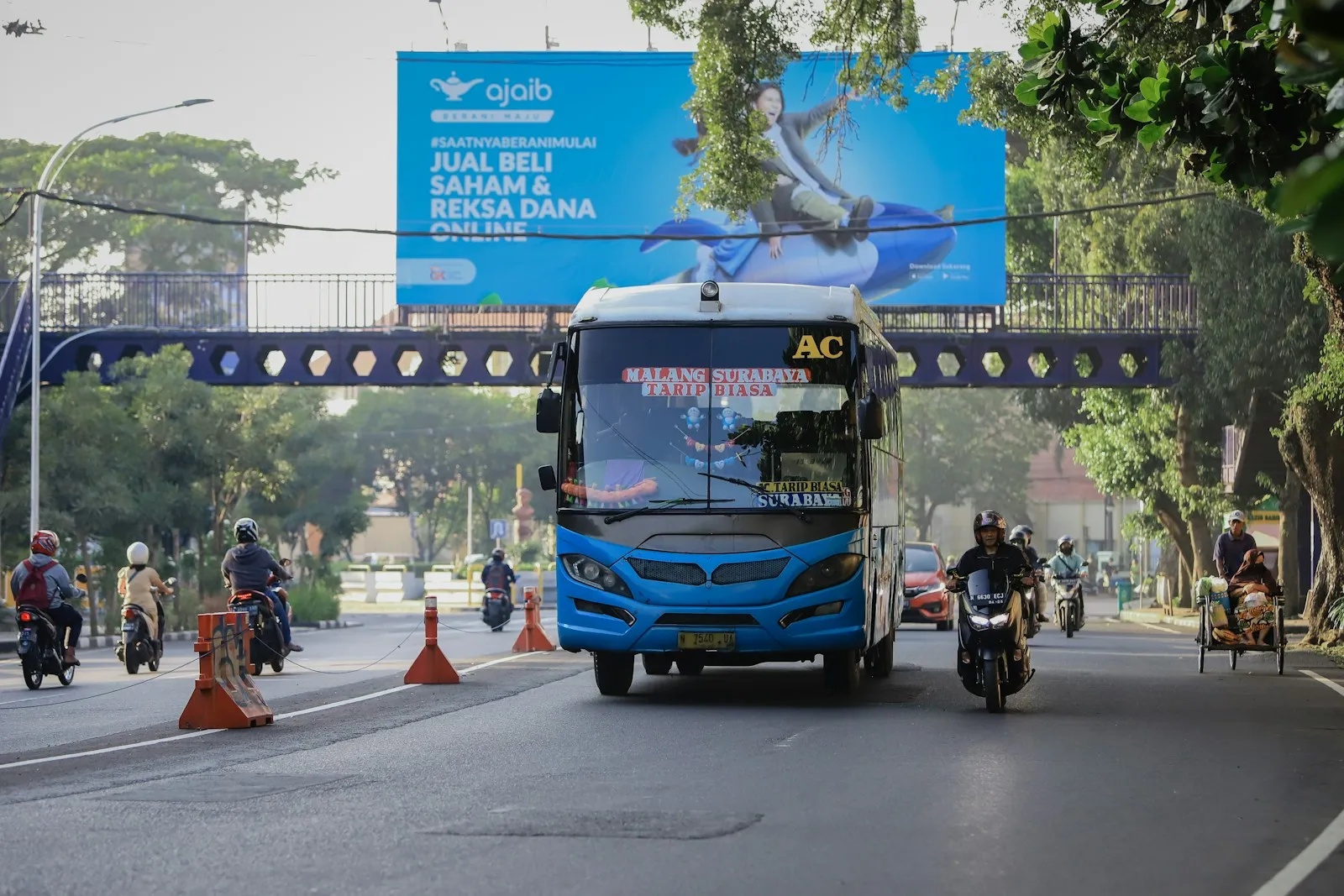 a blue bus driving down a street under a bridge