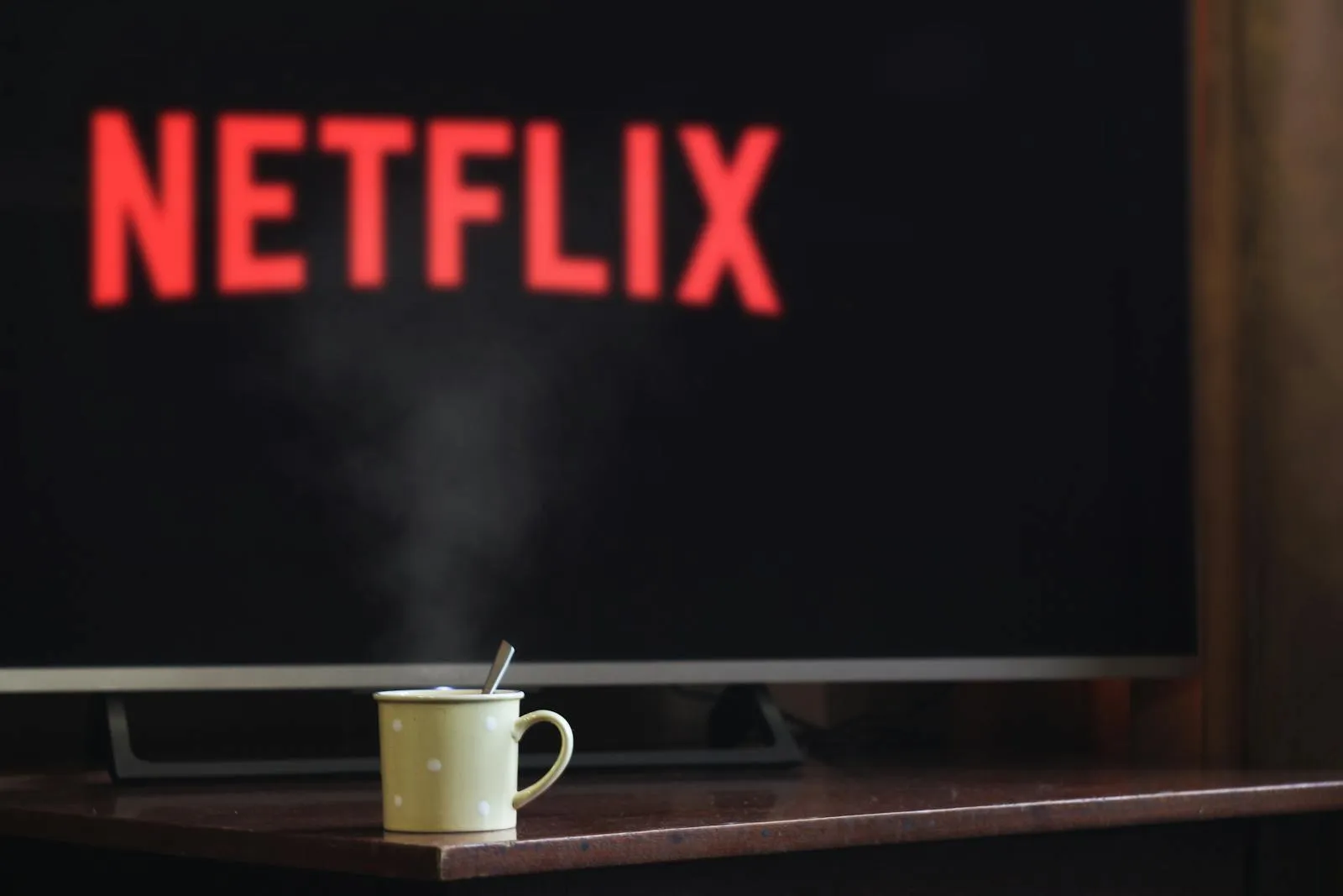 A steaming mug on a table in front of a TV displaying Netflix, creating a cozy indoor atmosphere.