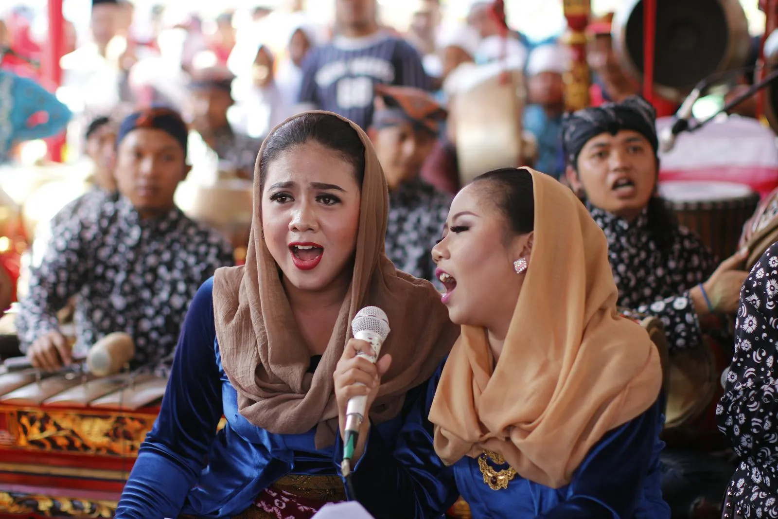 Women singing at a lively traditional music festival with performers.