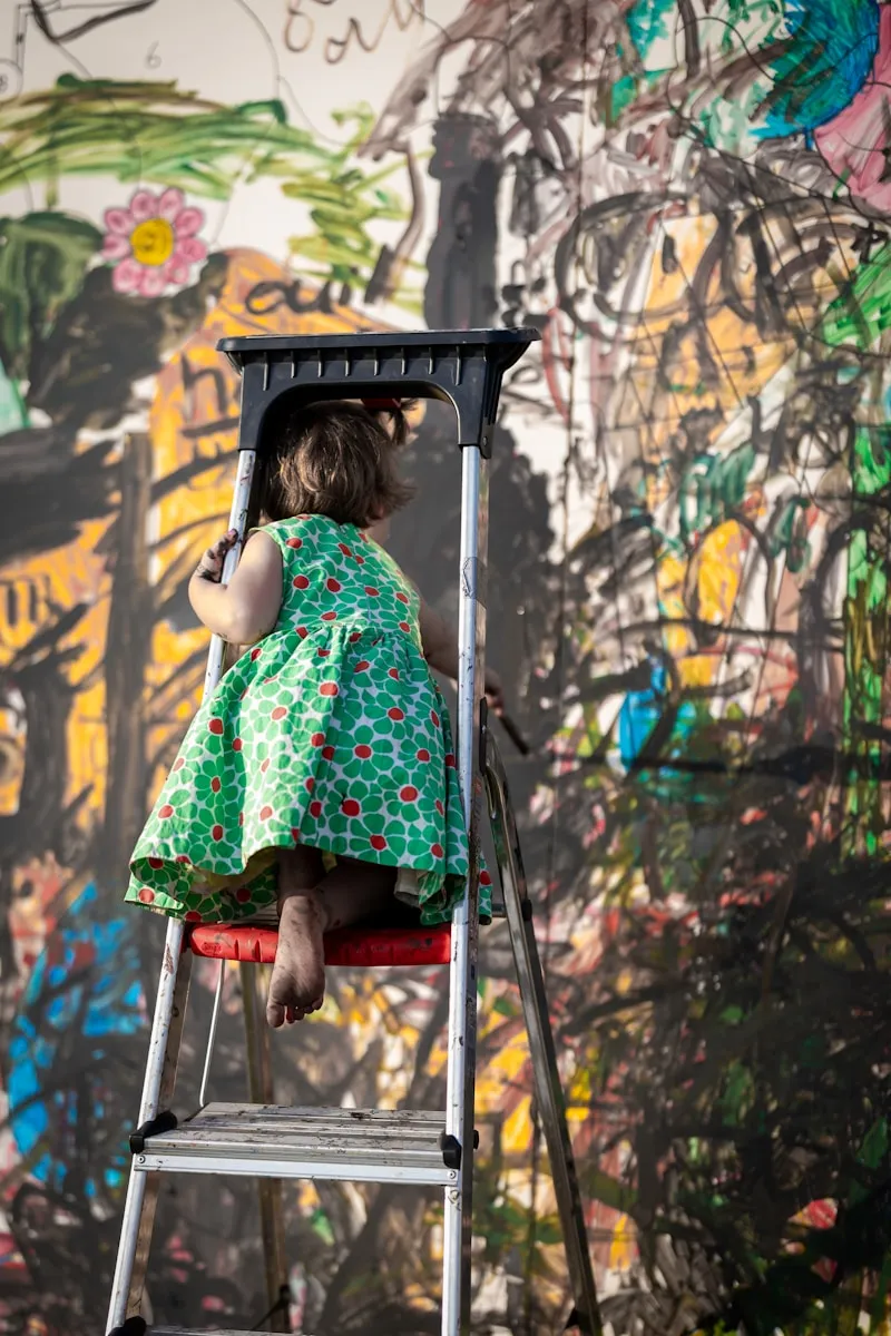 a little girl sitting on top of a ladder