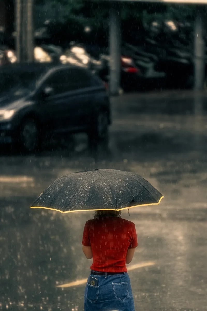 a woman standing in the rain with an umbrella