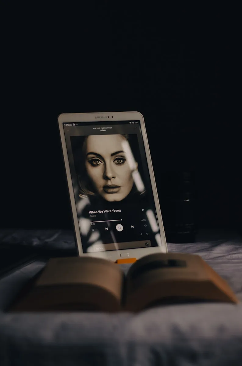 an open book sitting on top of a bed next to a laptop computer