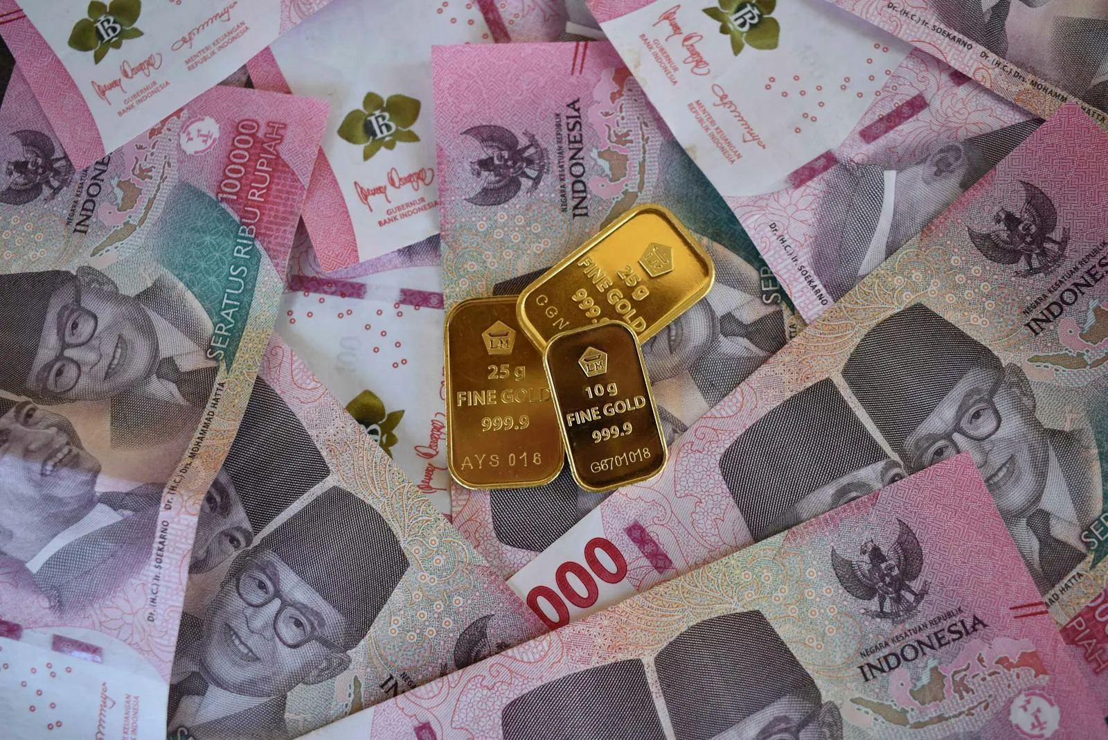 Close-up of Indonesian Rupiah banknotes with fine gold bars, symbolizing wealth and investment.